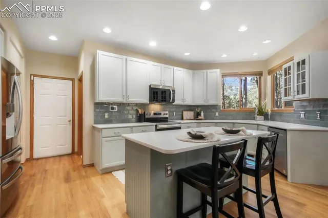 a kitchen with a sink a stove a refrigerator cabinets and a dining table with wooden floor