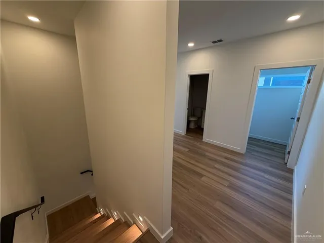 a view of a hallway with wooden floor and staircase