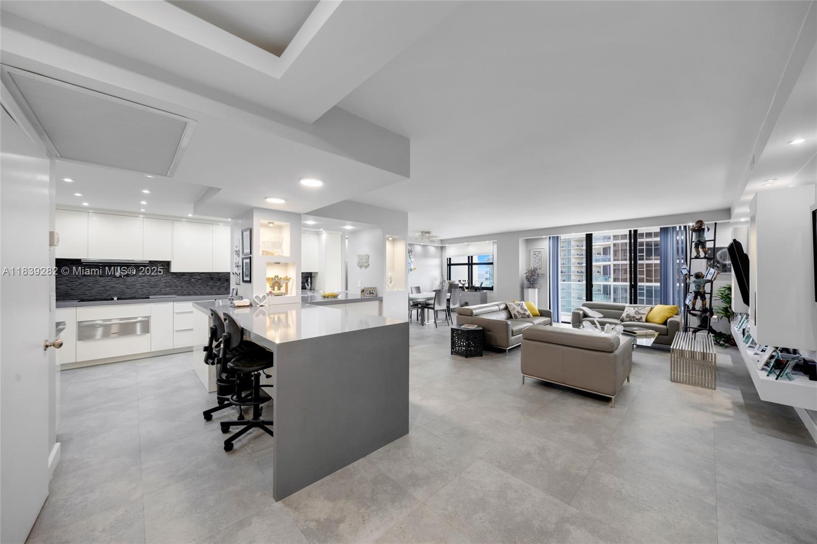 a living room with furniture kitchen view and a large window
