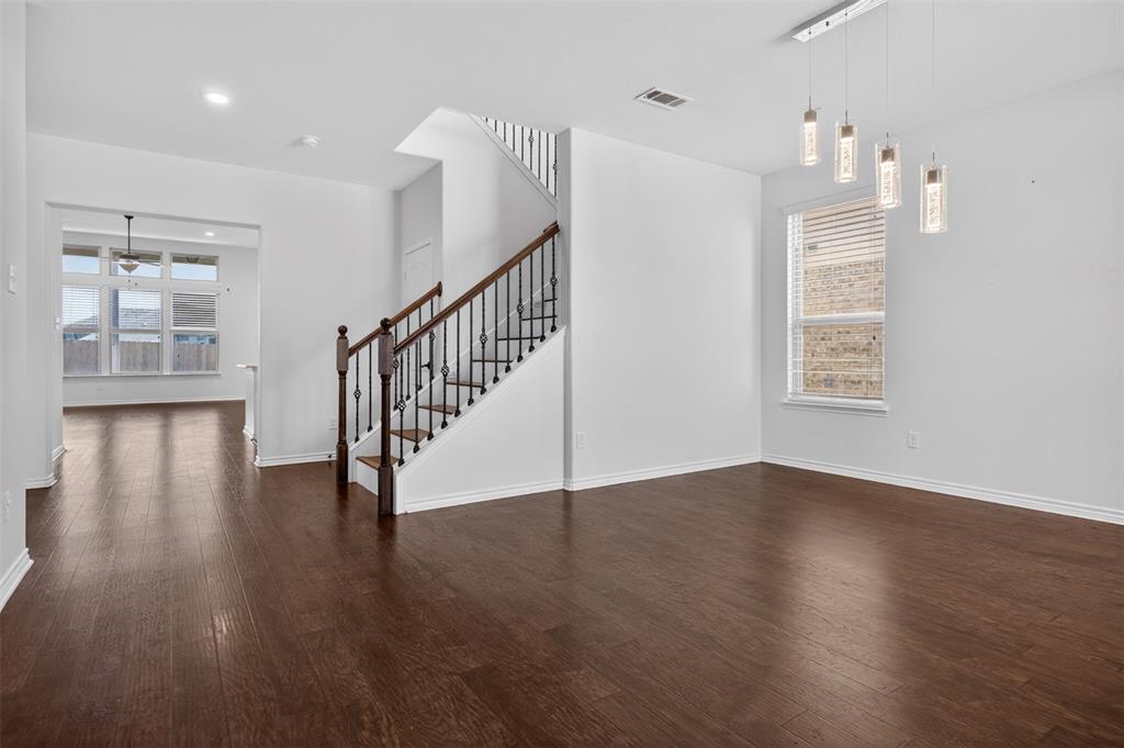 8728 Maple Ridge Trail Fort Worth, TX 76244 - Photo 9 of 40 Open-concept living area featuring wood-finish flooring, a contemporary staircase with iron balusters, a window with horizontal blinds, and a modern linear chandelier