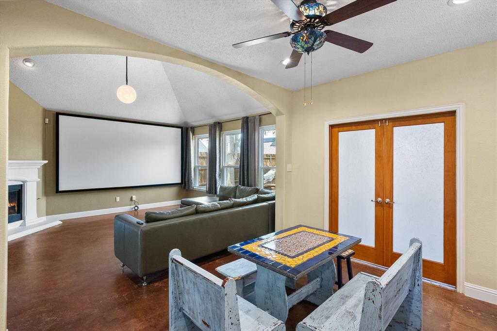 1305 Liverpool Lane Mansfield, TX 76063 - Photo 14 of 40 Living area featuring an arched entryway, a large projection screen, a white mantelpiece, and windows with drapery