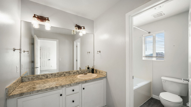 1285 Alpine Way Provo, UT 84606 - Photo 18 of 25 Granite-look countertop with an undermount sink, white cabinetry with dark hardware, and a large vanity mirror with overhead lighting