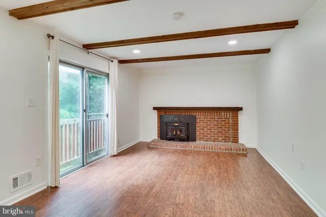 a view of a big room with wooden floor and a kitchen