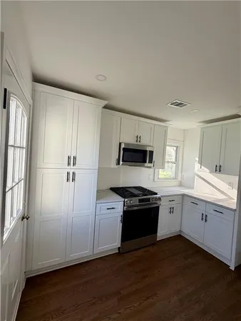 a kitchen with white cabinets and appliances