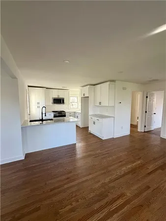 a view of kitchen and empty room with wooden floor