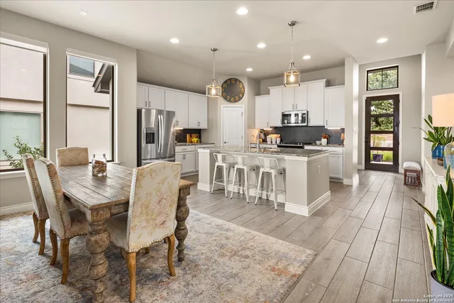 a kitchen with stainless steel appliances kitchen island granite countertop a stove a sink a dining table and chairs