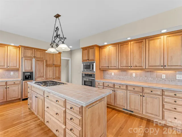 a kitchen with stainless steel appliances granite countertop a stove a sink dishwasher and refrigerator with wooden floor