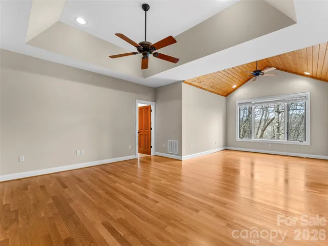 a view of an empty room with window and wooden floor