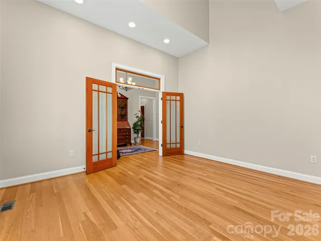 a view of empty room with wooden floor and fan