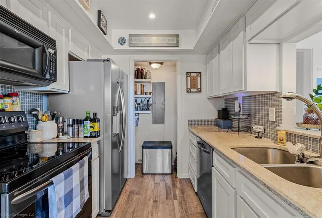 a kitchen with stainless steel appliances granite countertop a refrigerator a sink dishwasher a stove and a microwave oven with wooden floor