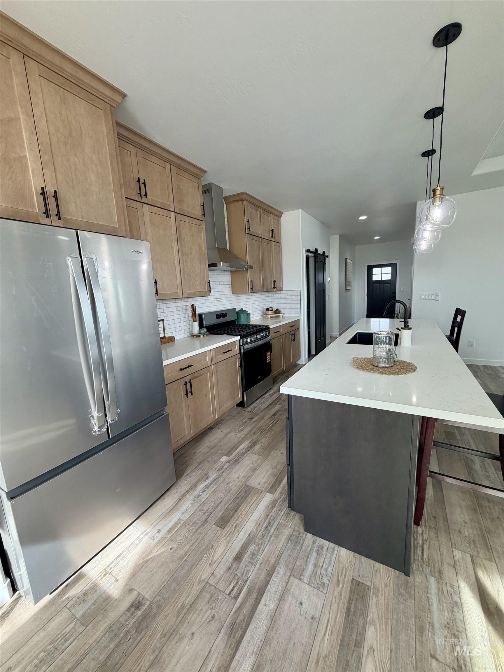 1419 Topaz Rupert, ID 83350 - Photo 10 of 41 Two tone kitchen featuring stainless steel appliances, decorative backsplash, an island with sink, two tone cabinetry, and a breakfast bar