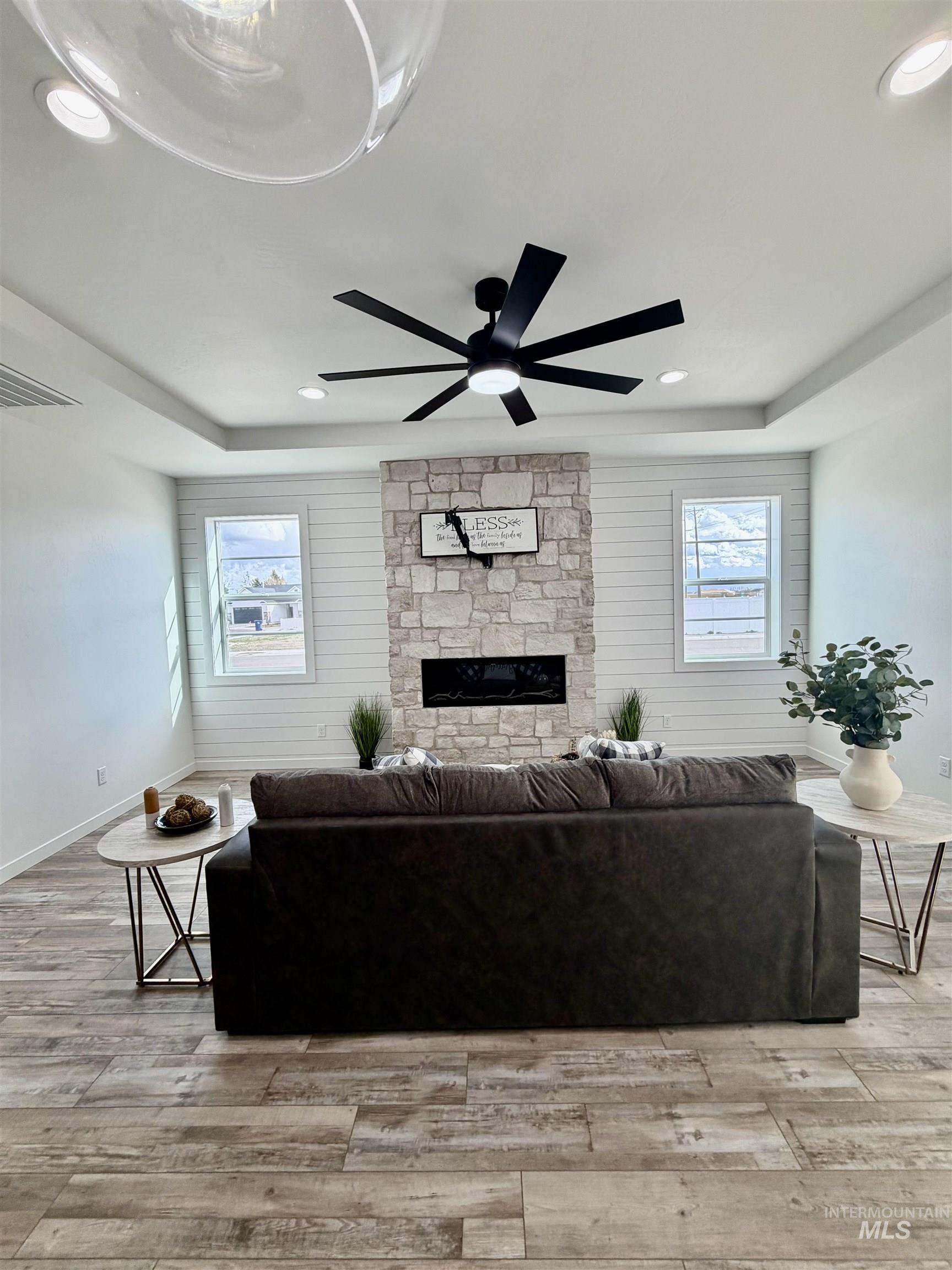 1419 Topaz Rupert, ID 83350 - Photo 12 of 41 Living area featuring a stone fireplace, light wood-style flooring, plenty of natural light, wood walls, and a ceiling fan