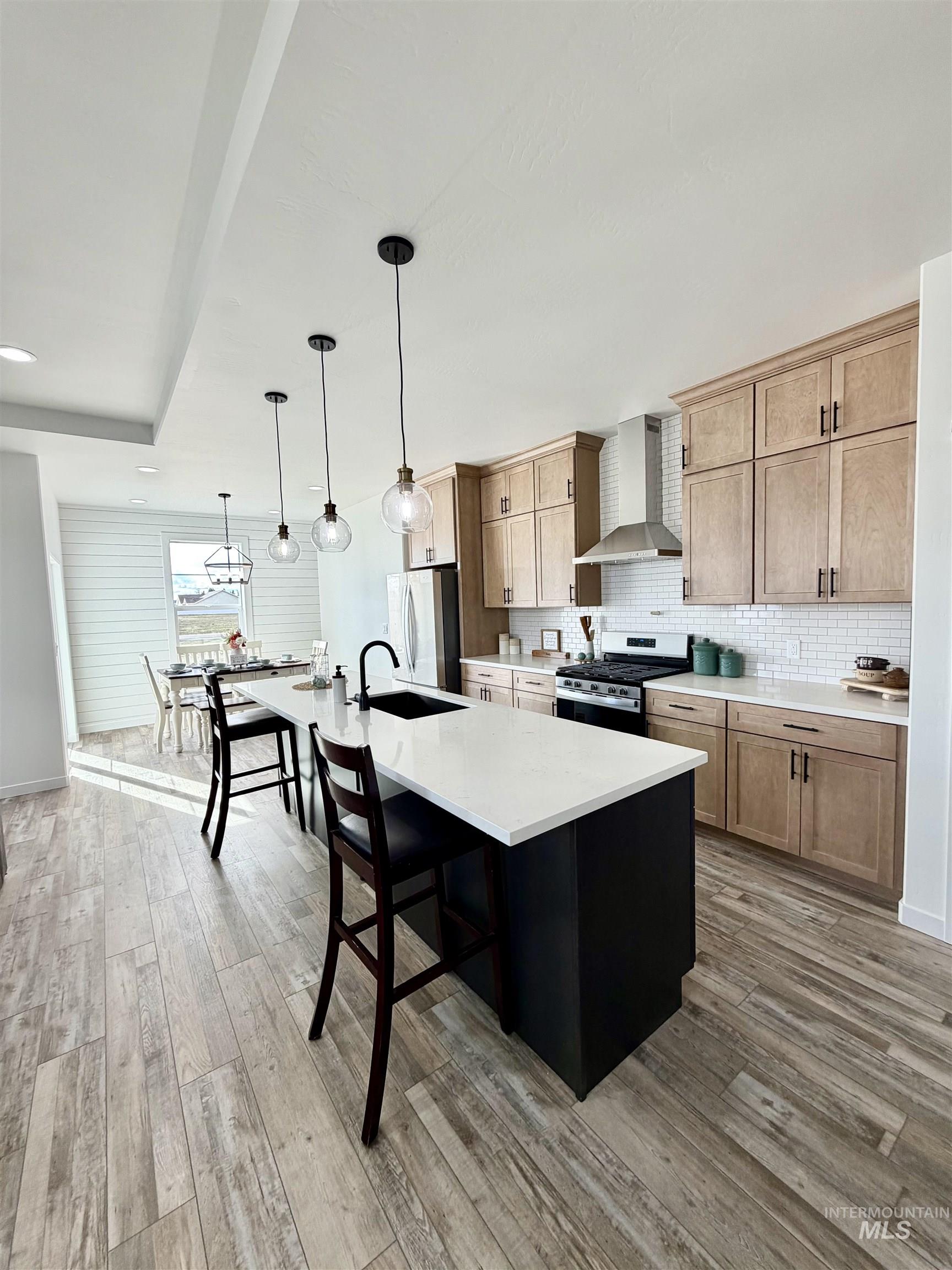 1419 Topaz Rupert, ID 83350 - Photo 26 of 41 Kitchen with stainless steel appliances, a center island with sink, two tone cabinetry, a breakfast bar area, and decorative light fixtures