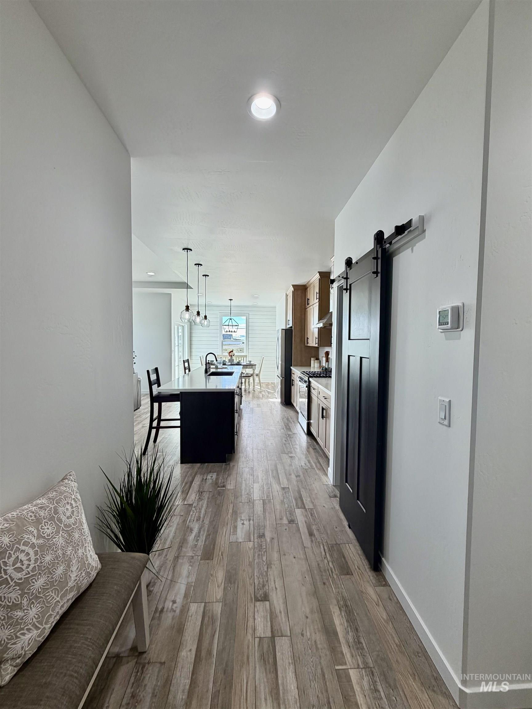1419 Topaz Rupert, ID 83350 - Photo 4 of 41 Two tone kitchen with a barn door, a center island with sink, hanging light fixtures, light wood finished floors, and light countertops