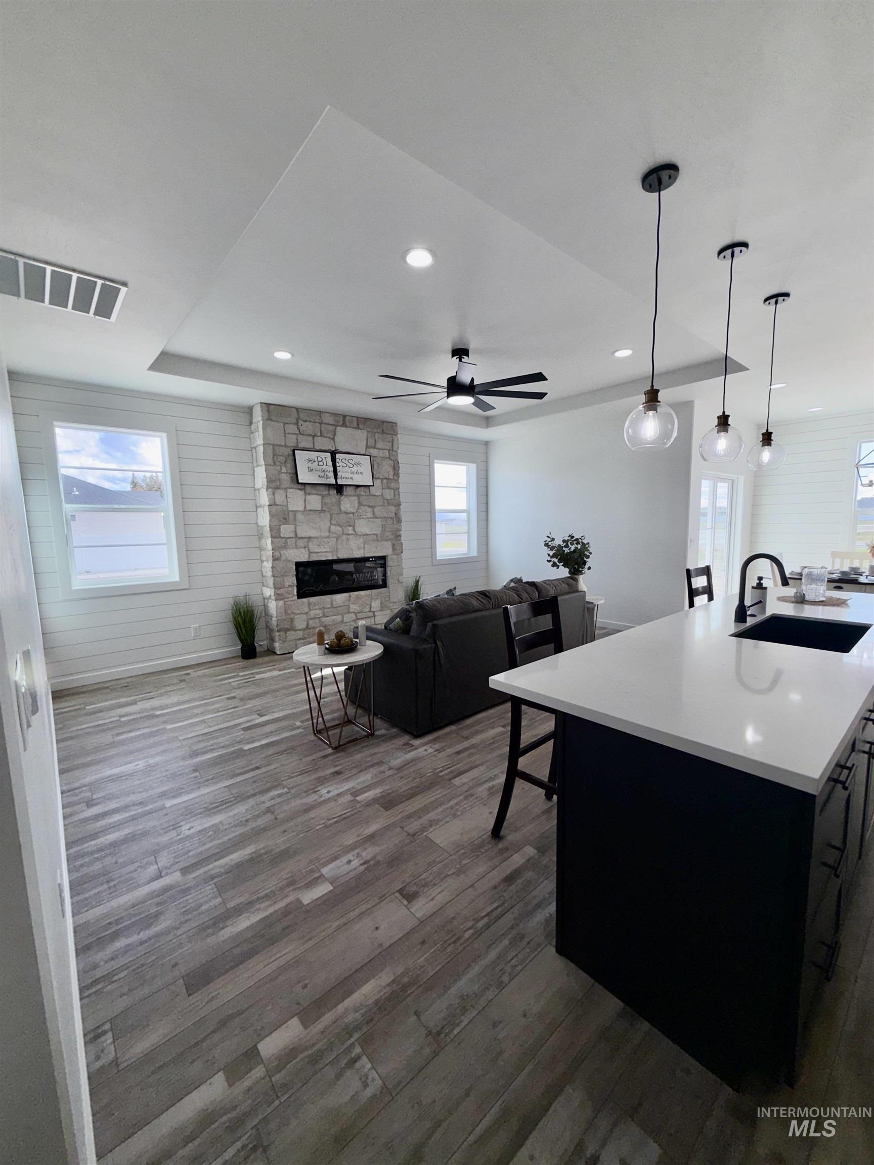 1419 Topaz Rupert, ID 83350 - Photo 39 of 41 Kitchen with open floor plan, a kitchen island with sink, dark cabinetry, hanging light fixtures, and a stone fireplace