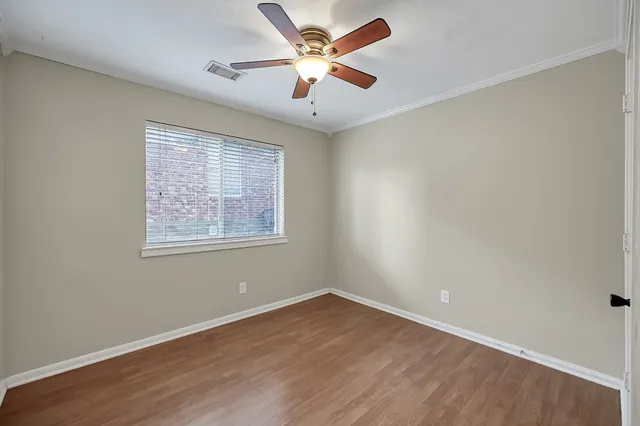 an empty room with wooden floor and ceiling fan