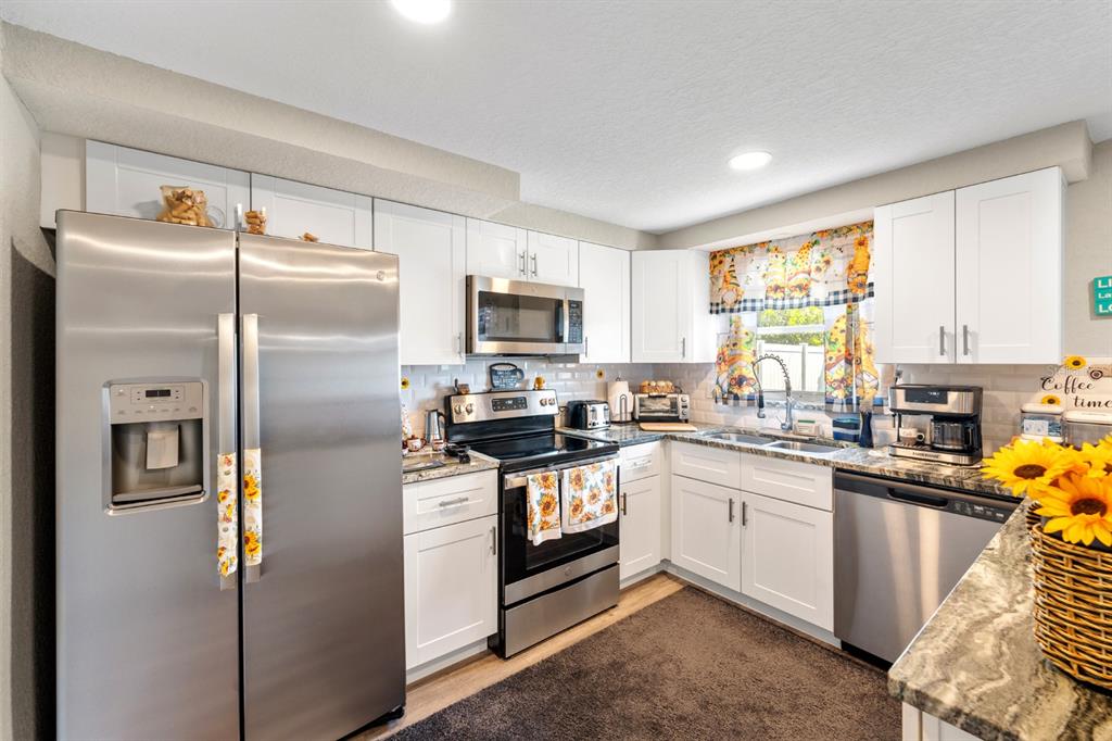 2152 Arcadia Road Holiday, FL 34690 - Photo 11 of 30 a kitchen with stainless steel appliances granite countertop a refrigerator a sink a stove a chimney a refrigerator and cabinets