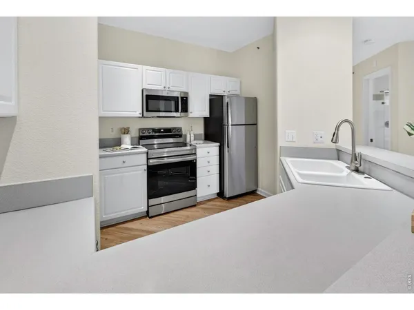 a kitchen with stainless steel appliances a stove a sink and white cabinets