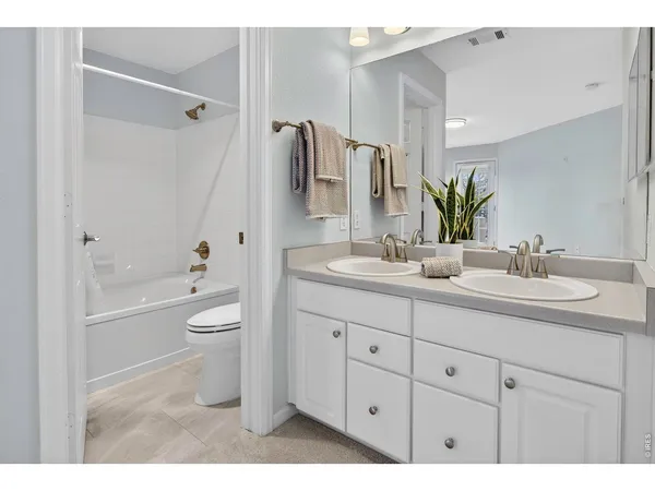 a bathroom with a sink double vanity granite tub and a toilet