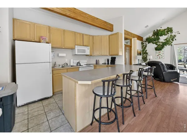 a kitchen with sink a refrigerator and chairs