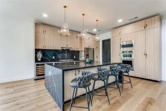 a kitchen with stainless steel appliances kitchen island granite countertop a table chairs and a refrigerator