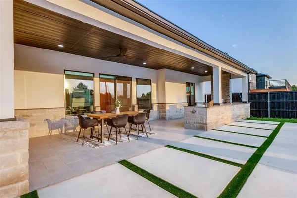 a view of a patio with a dining table and chairs with wooden floor and fence