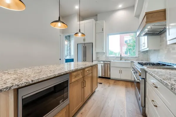 a kitchen with stainless steel appliances granite countertop a stove a sink a refrigerator and chairs