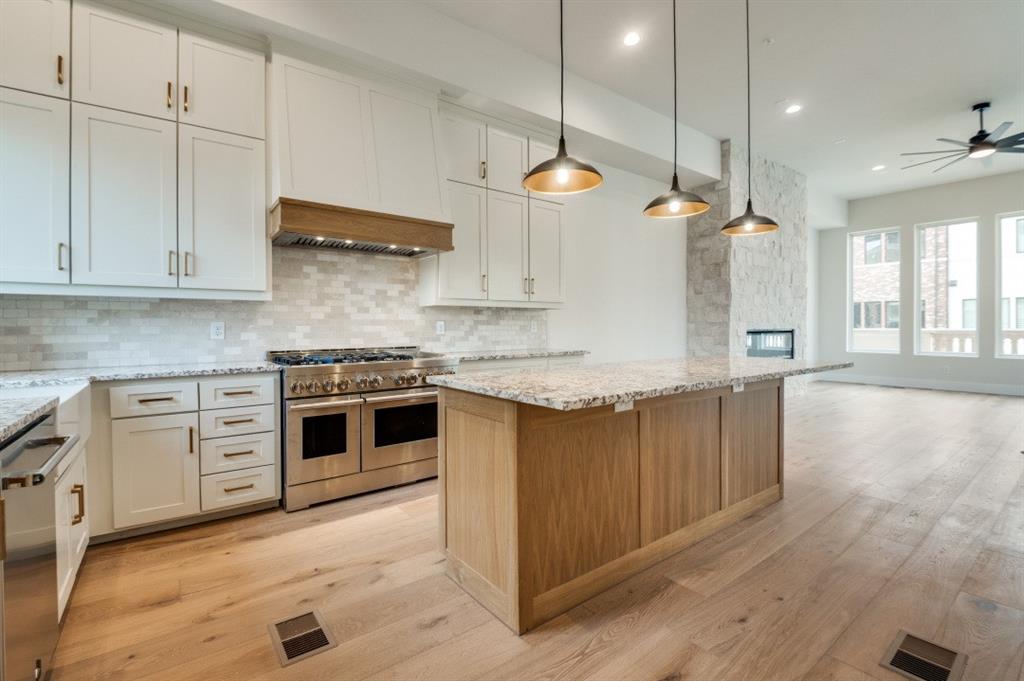 250 East Dallas Road, Unit 121 Grapevine, TX 76051 - Photo 17 of 34 a kitchen with granite countertop a stove a sink and white cabinets with wooden floor