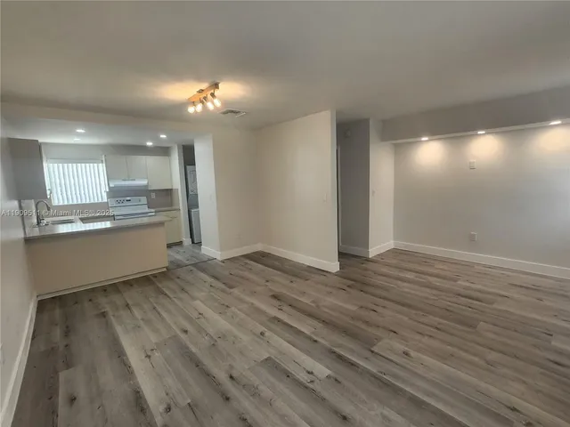 a view of a kitchen with a sink and dishwasher a refrigerator with wooden floor