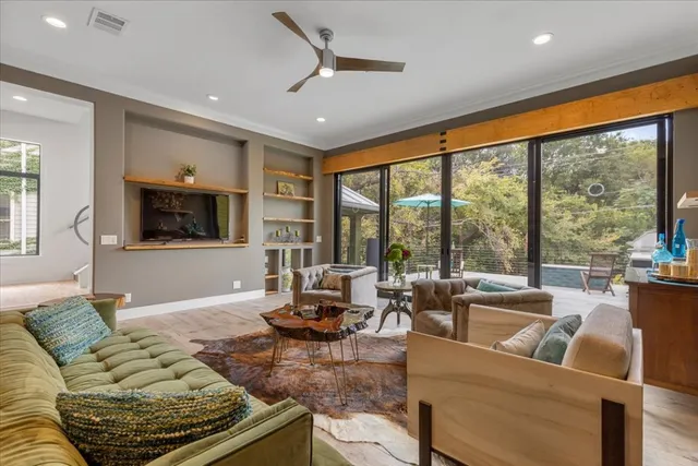 a living room with furniture floor to ceiling window hardwood floor and a flat screen tv