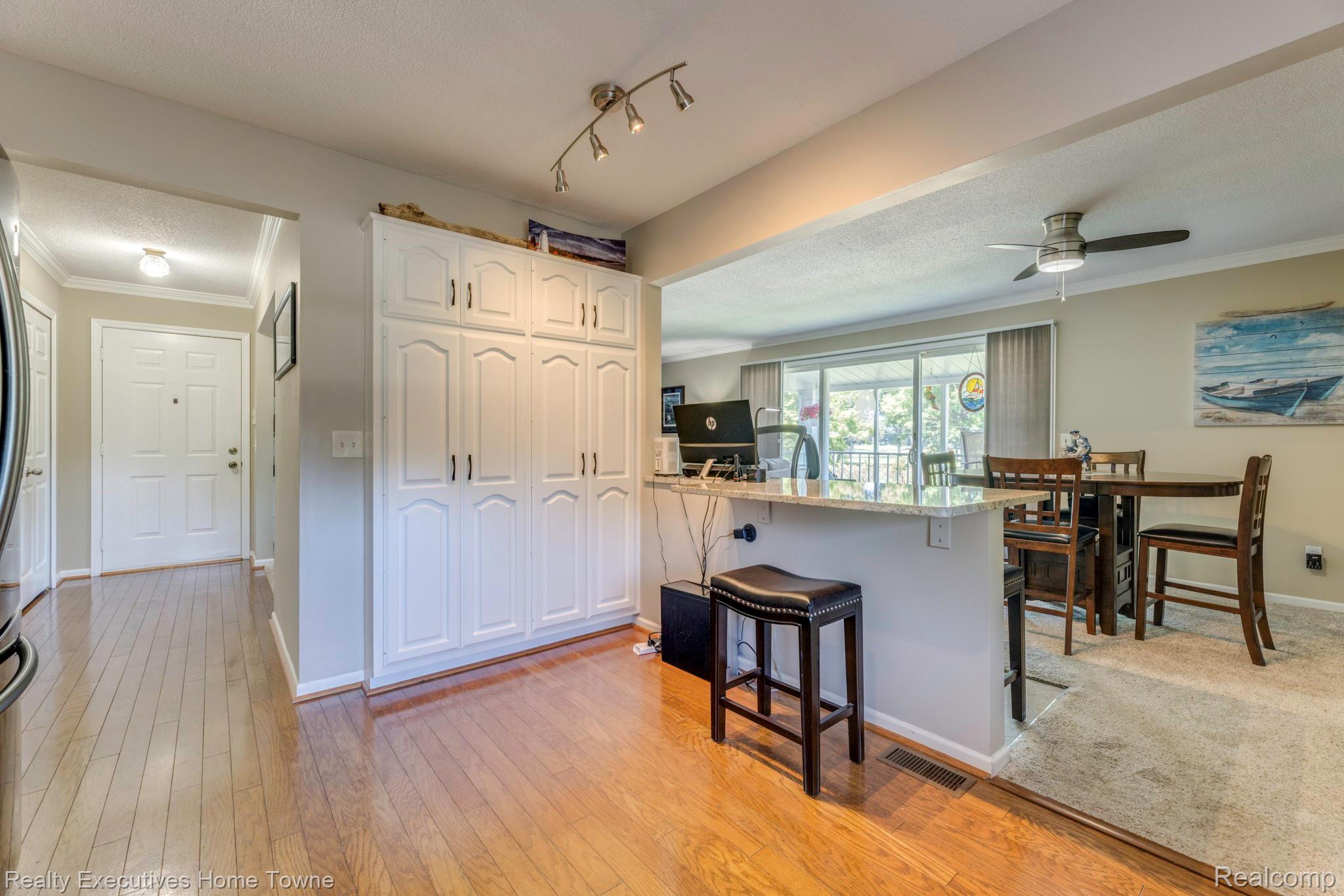 1467 Krafft Road, Unit 8 Port Huron, MI 48060 - Photo 14 of 30 Open-concept living space with wood-finish flooring, white built-in cabinetry, a kitchen island with stone countertop, and glass sliding doors leading to an outdoor area