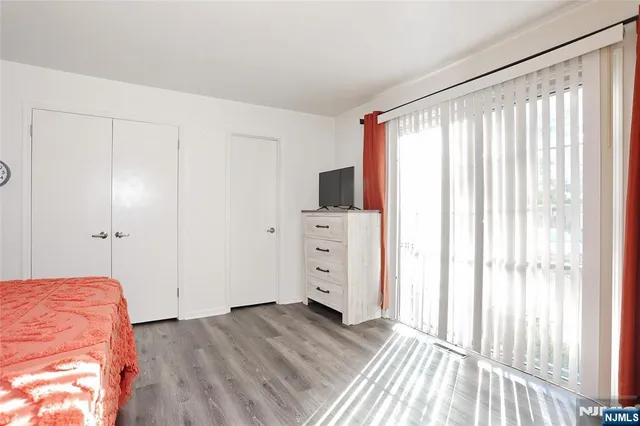 a view of a bedroom with wooden floor and windows