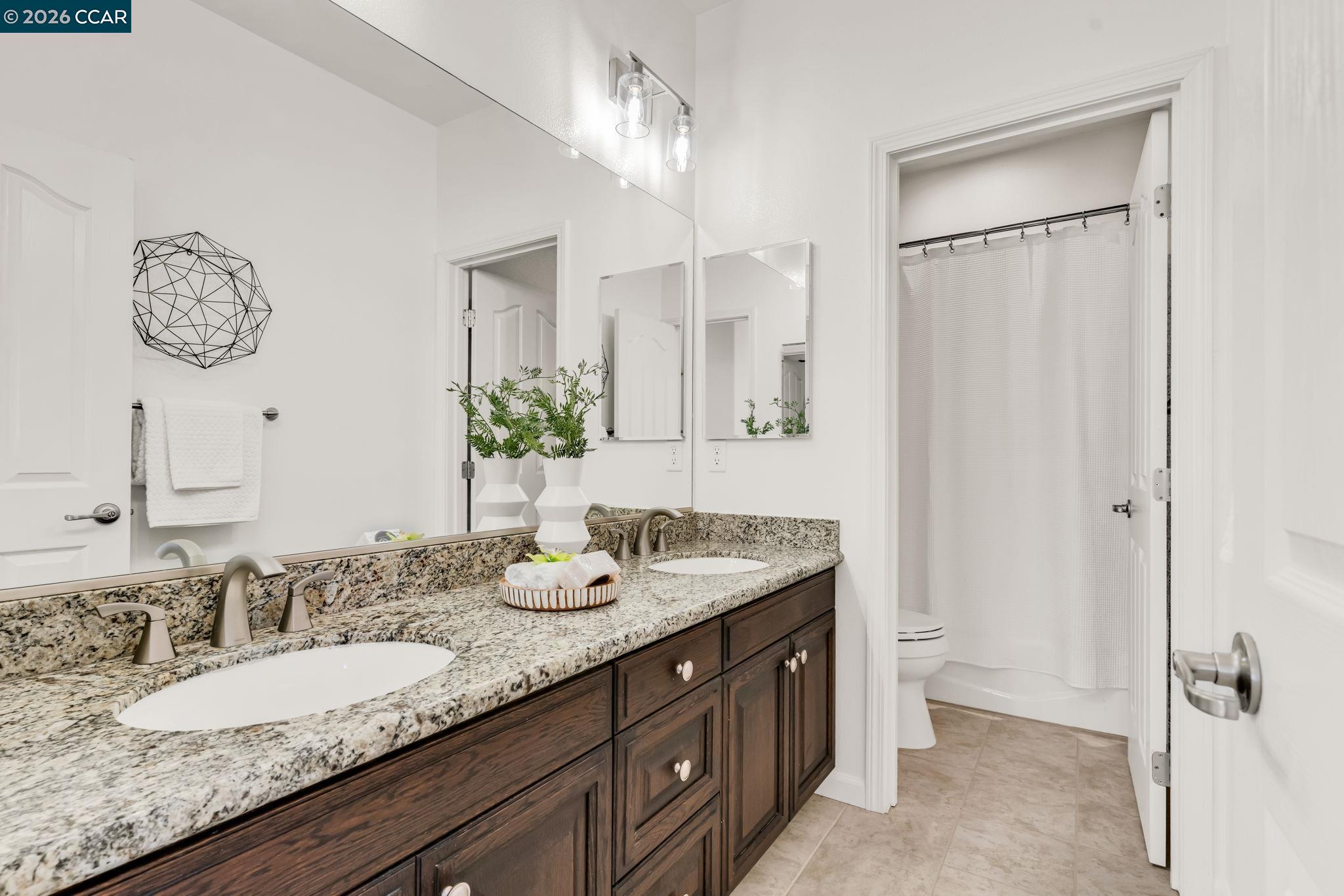 116 Spalding Court San Ramon, CA 94582 - Photo 44 of 59 a bathroom with double vanity sinks a toilet a mirror and shower