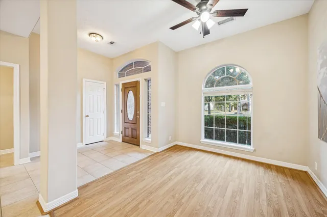 an empty room with wooden floor chandelier and windows