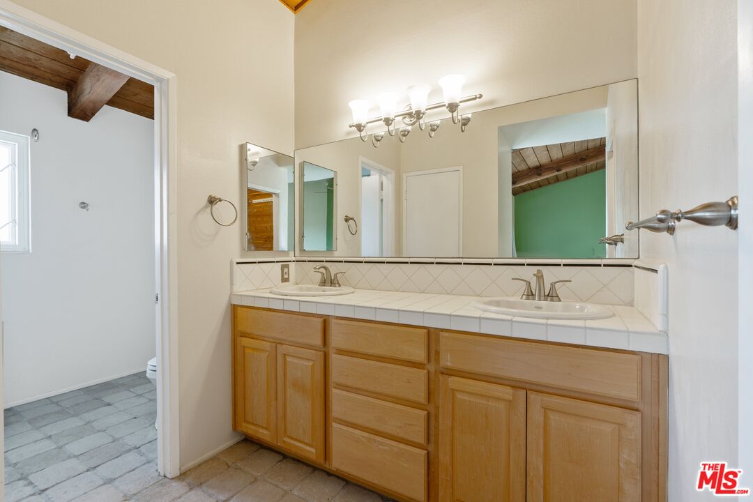 28244 Rey De Copas Lane Malibu, CA 90265 - Photo 16 of 31 a bathroom with a double vanity sink and mirror