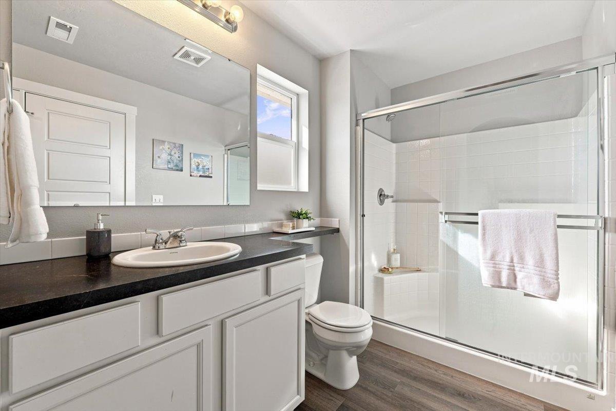 696 East Springloyd Street Meridian, ID 83642 - Photo 26 of 37 White vanity with dark countertop, large mirror, and wood-finish flooring