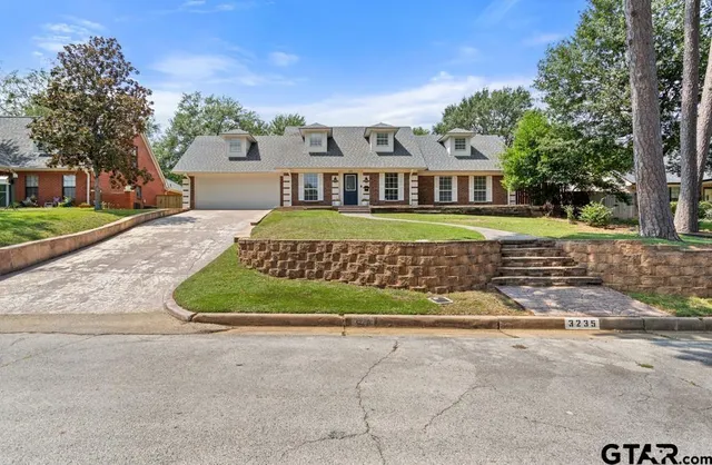 a view of a house with a yard and large trees