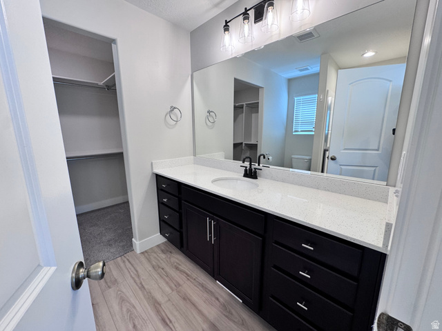 12339 Remy Road, Unit 422 Herriman, UT 84096 - Photo 24 of 36 Full bathroom with a spacious closet, vanity, and light wood-style flooring