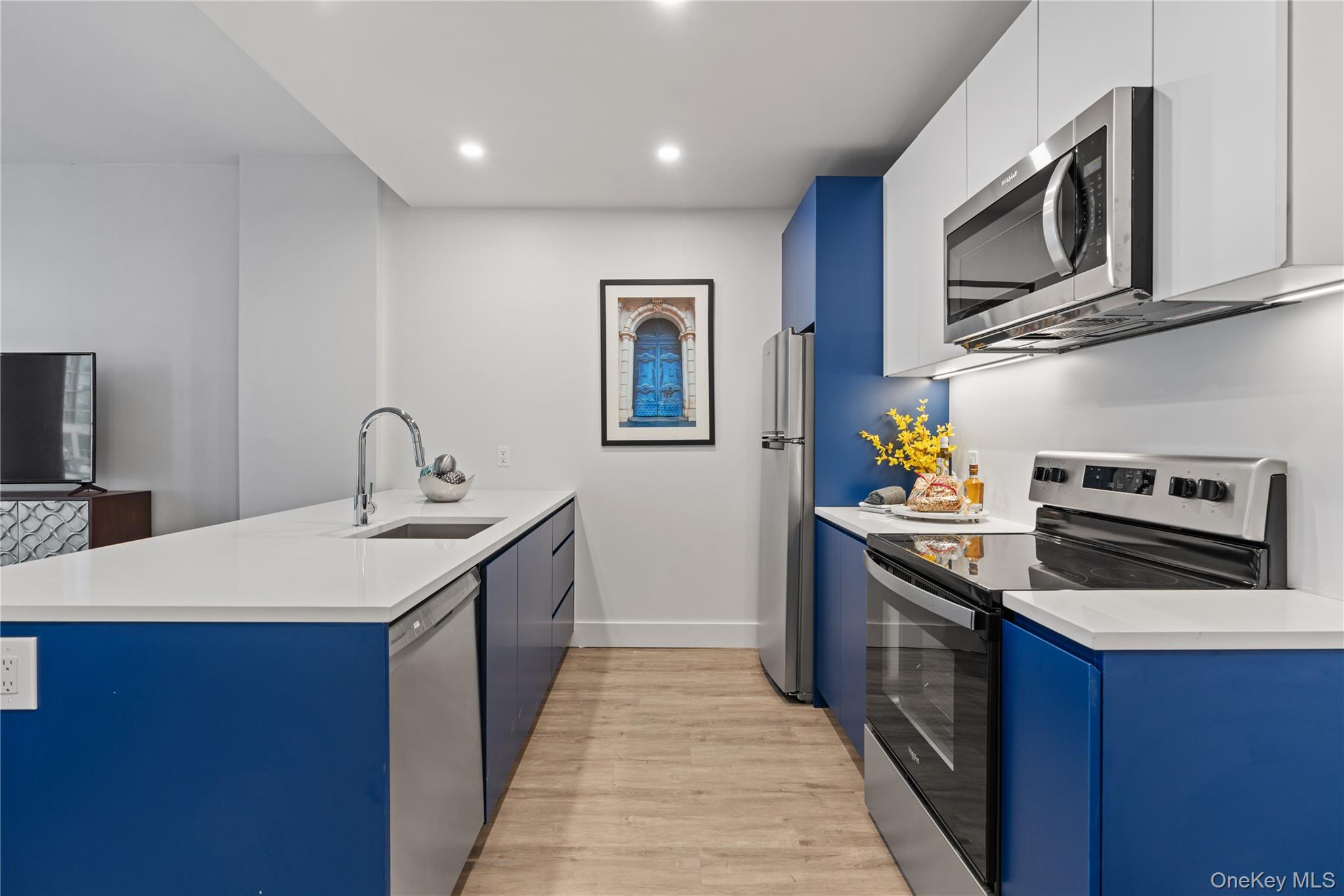 Kitchen with stainless steel appliances, blue cabinetry, a peninsula, modern cabinets, and recessed lighting