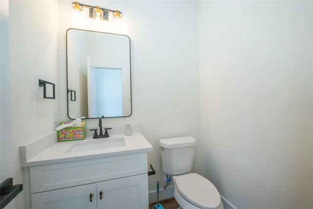 a bathroom with a toilet sink vanity and mirror