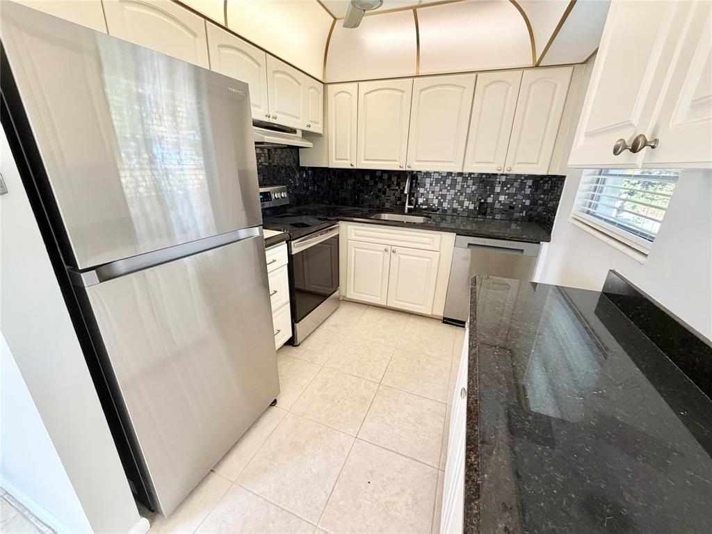 84 Mansfield A, Unit 84 Boca Raton, FL 33434 - Photo 4 of 24 a kitchen with stainless steel appliances a refrigerator a sink and white cabinets