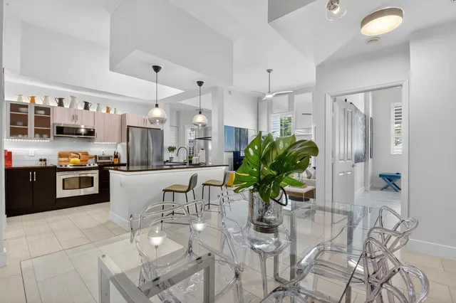 a kitchen with stainless steel appliances granite countertop a refrigerator a sink dishwasher a dining table and chairs with wooden floor