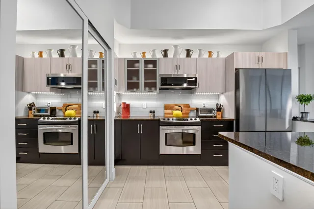 a kitchen with stainless steel appliances granite countertop a refrigerator a stove and a sink