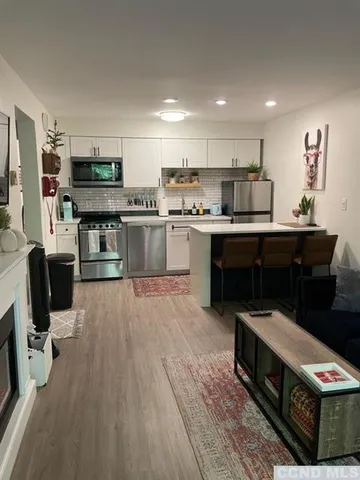 a kitchen with stainless steel appliances granite countertop a refrigerator a stove top oven a sink dishwasher and white cabinets with wooden floor