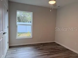 a view of an empty room with wooden floor and a window