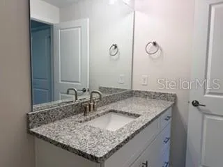a bathroom with a granite countertop sink and a mirror