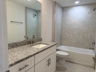 a bathroom with a granite countertop sink a toilet and bathtub