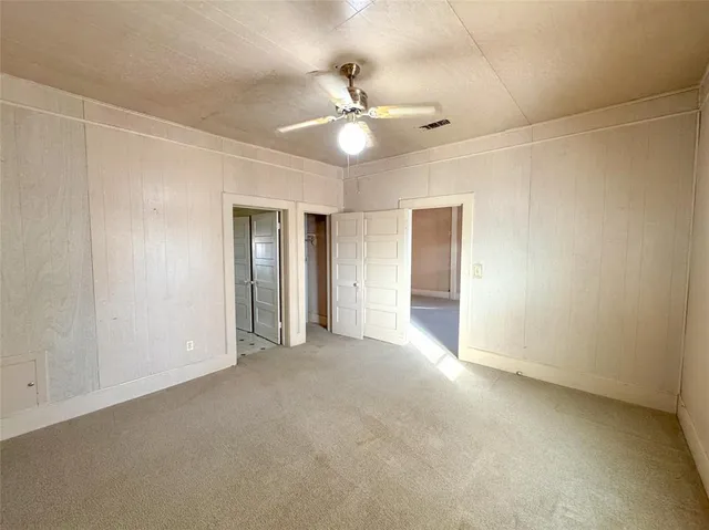 an empty room with closet and a ceiling fan