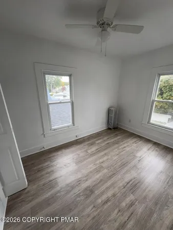 an empty room with wooden floor cabinet and windows