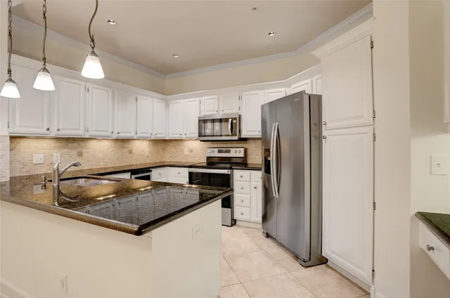 a kitchen with granite countertop a refrigerator a sink a stove and cabinets